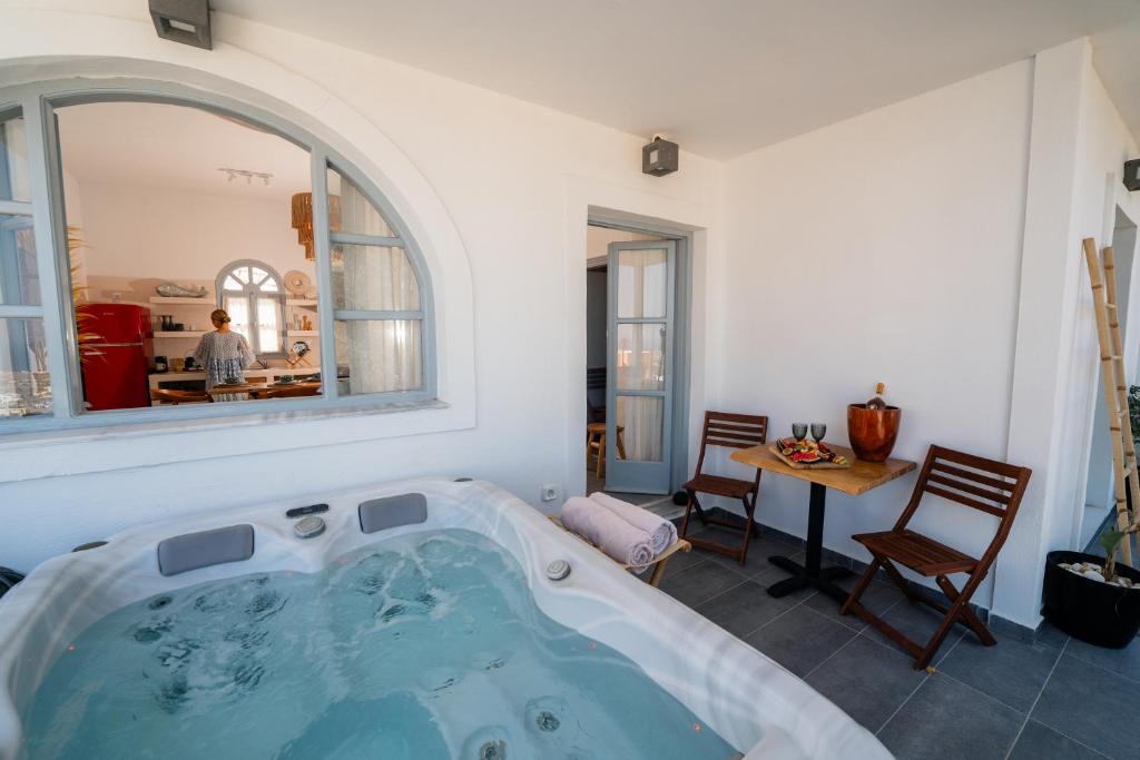 a bath tub in a room with a table and chairs at Divino Suites in Fira