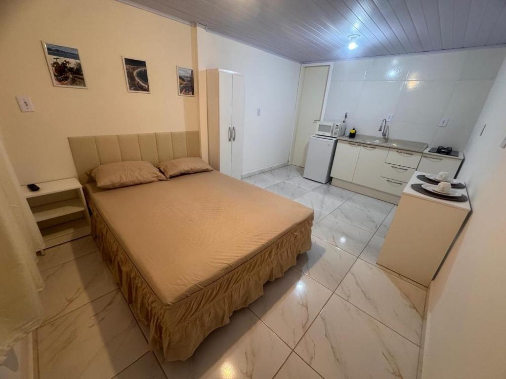 een kleine slaapkamer met een bed en een keuken bij Studios Cordeiros in Itajaí