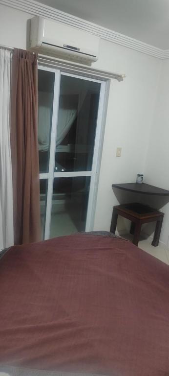 Un dormitorio con una cama y una ventana y una mesa. en Suíte na rua da praia, en Porto Belo