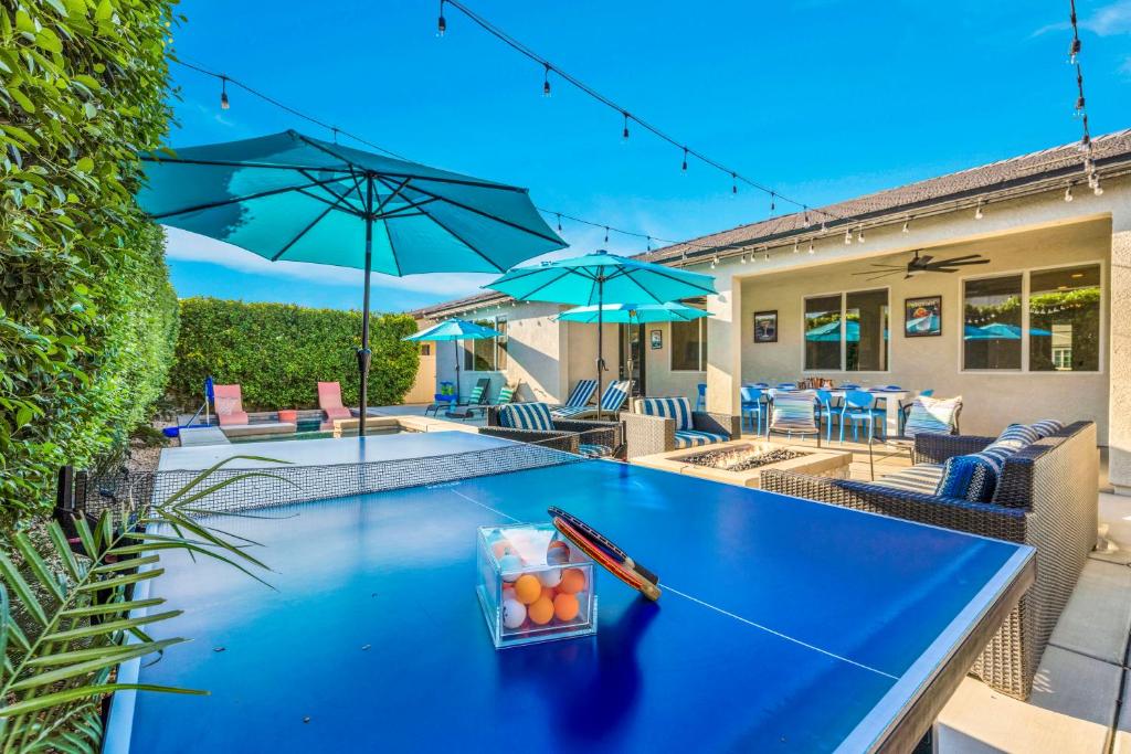 a blue ping pong table with umbrellas on a patio at Turquoise Mirage Fun House in Indio