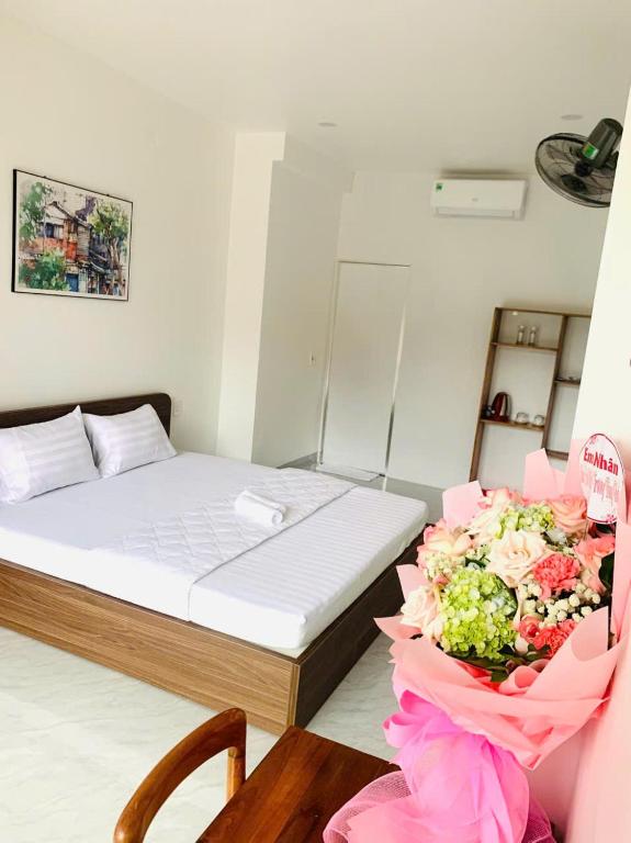 a small room with a bed with a bouquet of flowers at Hiên's Homestay in Hue