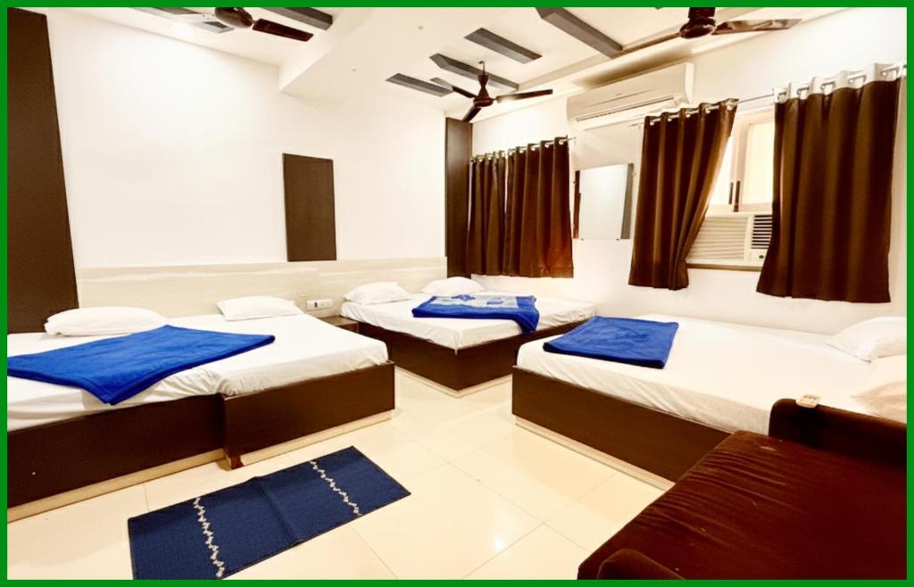 a room with three beds and a couch in it at Mahakaleshwar jyotilinga Temple Dwarika - Dhish Premium near Railway station, Fully Air conditioned Rooms -wifi- Lift and Restaurant Facilities, BEST HOTEL IN UJJAIN in Ujjain
