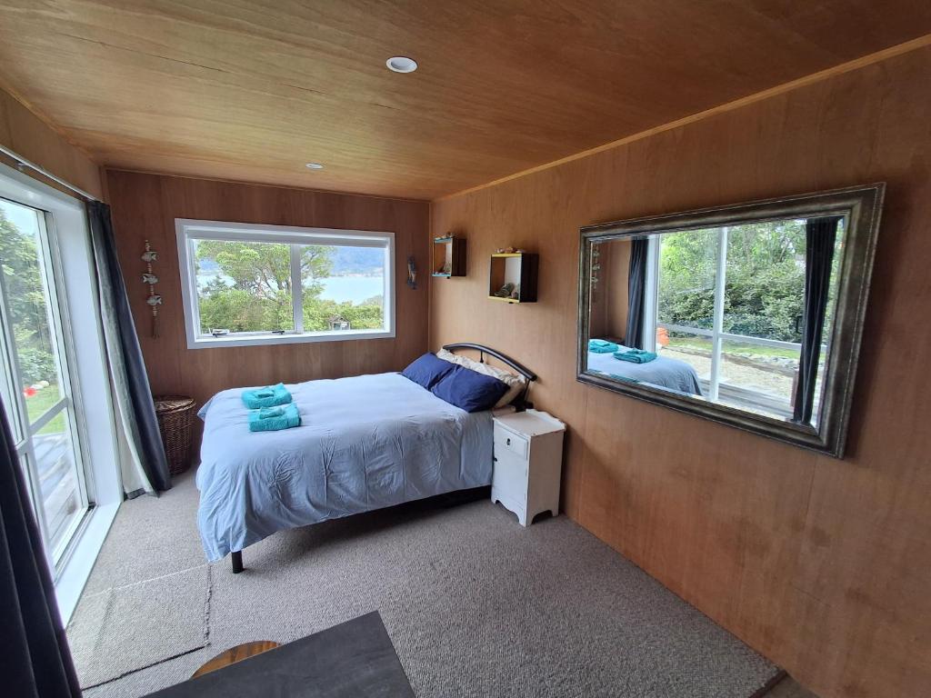 a small bedroom with a bed and two windows at Tairua Getaway in Tairua