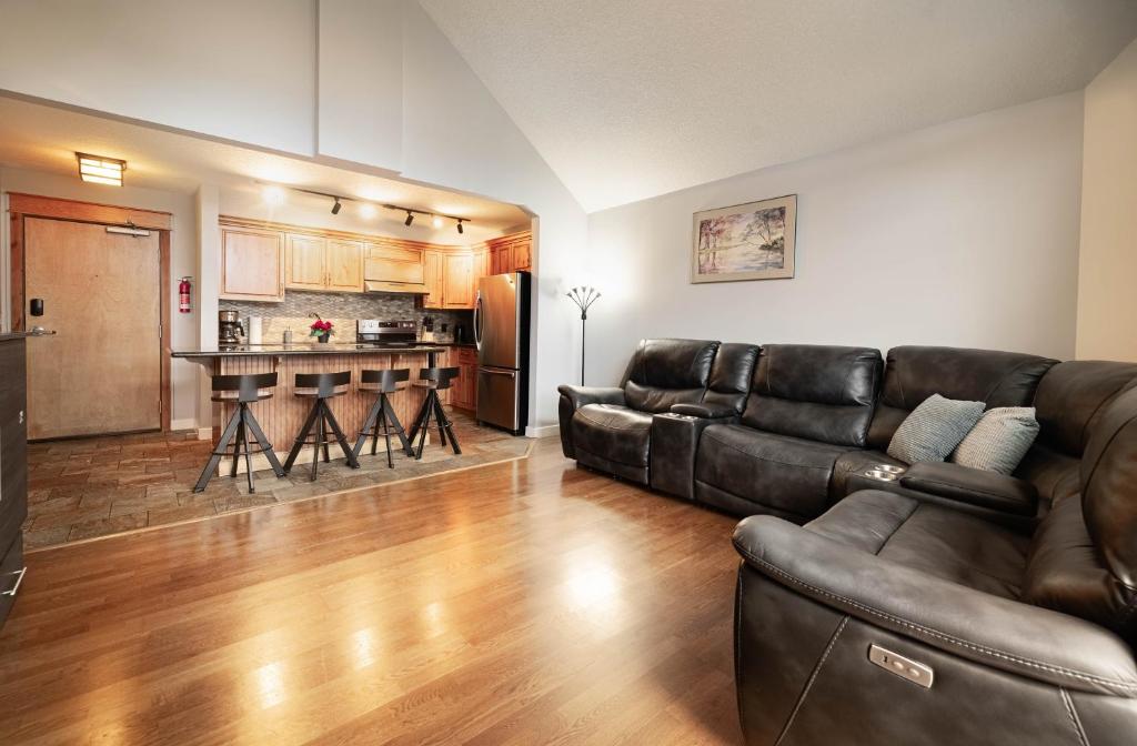 een woonkamer met een leren bank en een keuken bij Rocky Mountain Retreat-Mountain View! in Canmore