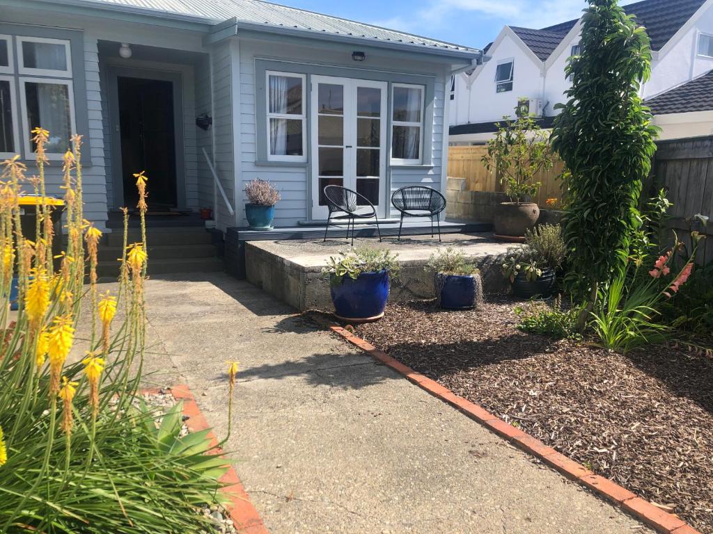 a house with a patio and flowers in the yard at Cambria Cottage in Nelson