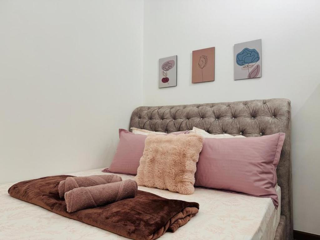 ein Bett mit rosa und lila Kissen darauf in der Unterkunft Mirai Residence Kajang 2 UKM Bangi GMI in Kajang