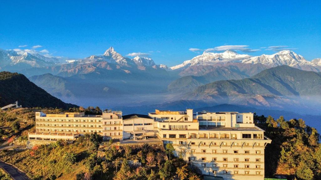 a building on a hill with mountains in the background at Hotel Annapurna View Sarangkot in Pokhara
