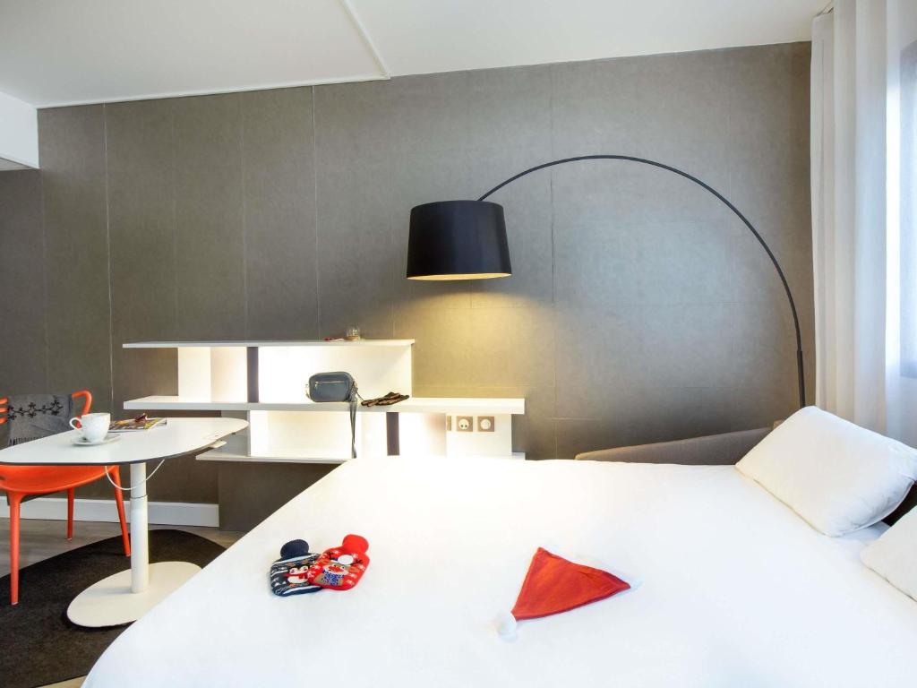 a bedroom with a white bed and a table and a chair at Novotel Suites Perpignan Centre - Grandes Suites & Confort Centre-Ville in Perpignan