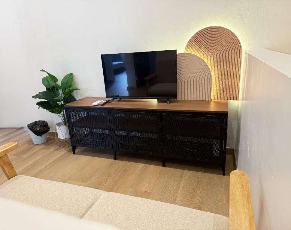 a living room with a television on a wooden cabinet at relaxing home in Bukit Mertajam in Bukit Mertajam