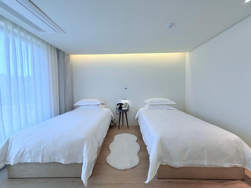 two beds sitting next to each other in a bedroom at 제주 신성의 숲 웰니스 호텔 in Haean