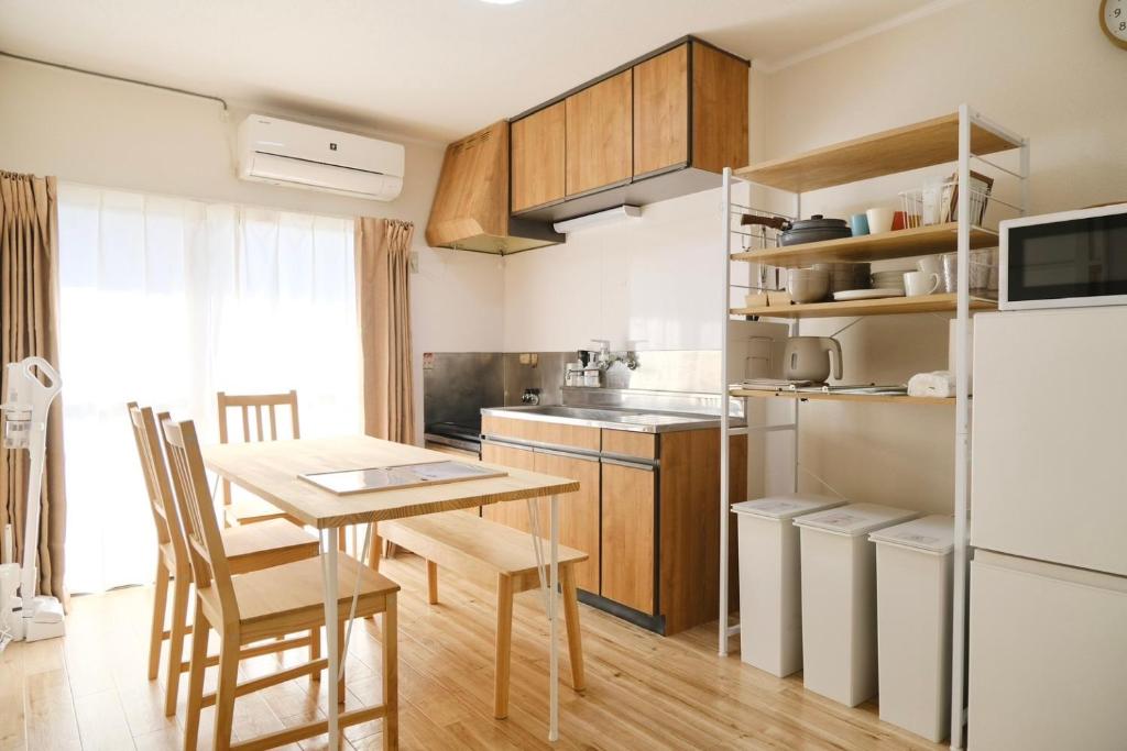 een keuken met een tafel en een koelkast bij 駅近商業施設近くで便利 静かで心ほぐれる滞在が叶う宿neuk Hill 定員5名 無料駐車場有 in Fukuroi