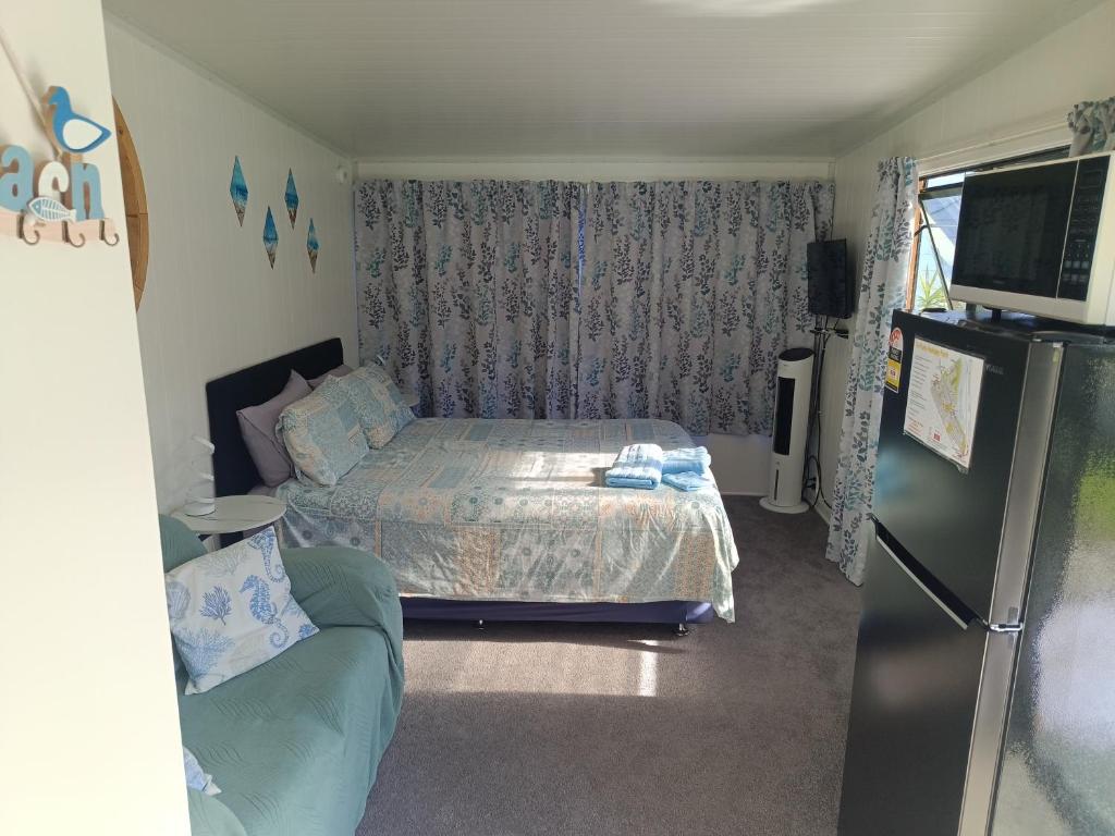 a small bedroom with a bed and a refrigerator at Riverview Studio in Te Puru