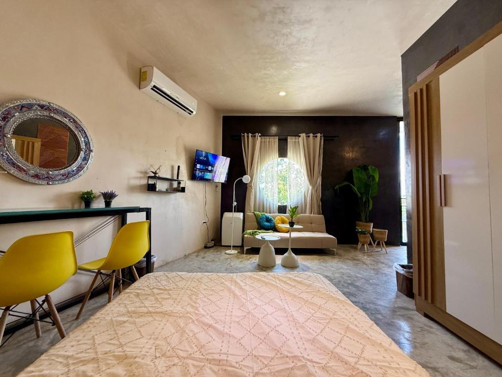 una sala de estar con una cama grande y sillas amarillas en Departamento Belembi merida, en Mérida