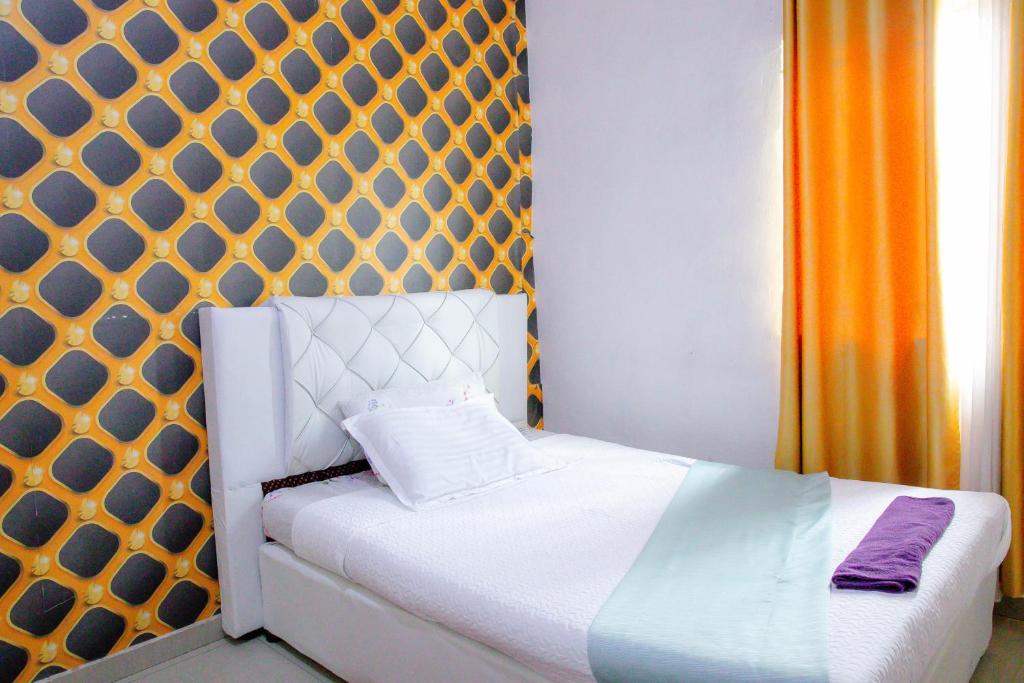 a bedroom with a white bed with an orange curtain at Villa guest house in Ndola