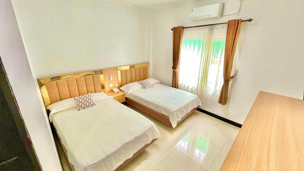 a small room with two beds and a window at Berlian Guest House Syari'ah in Martapura