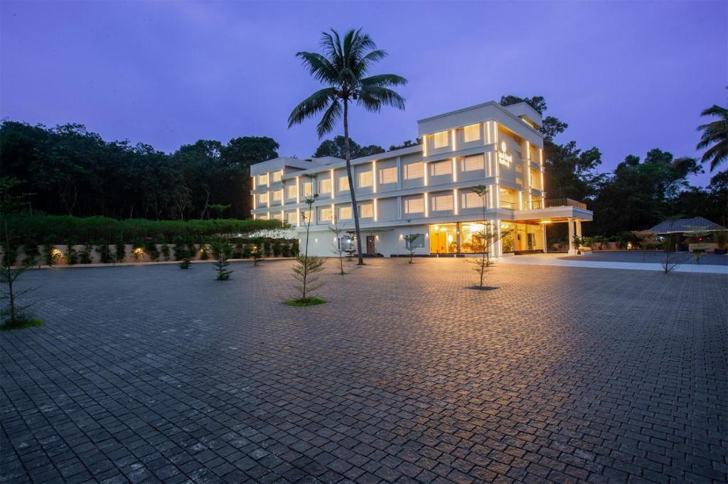 Grand Royal Residency في Pala: مبنى كبير أمامه نخلة