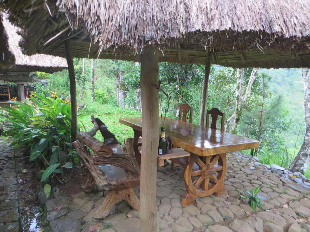 a wooden table and chairs under a hut at Native Village Inn in Banaue