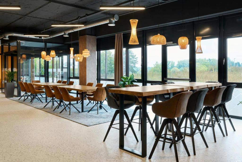 a group of tables and chairs in a room with windows at Four Points Flex by Sheraton Östringen in Östringen