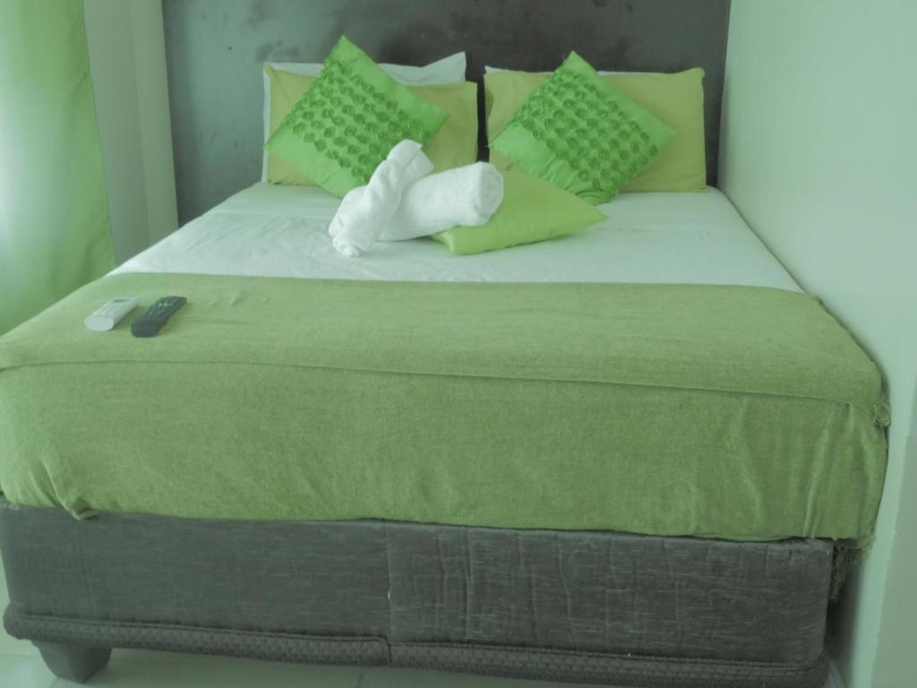 1 cama con edredón y almohadas verdes en Valley Guest House, en Pretoria