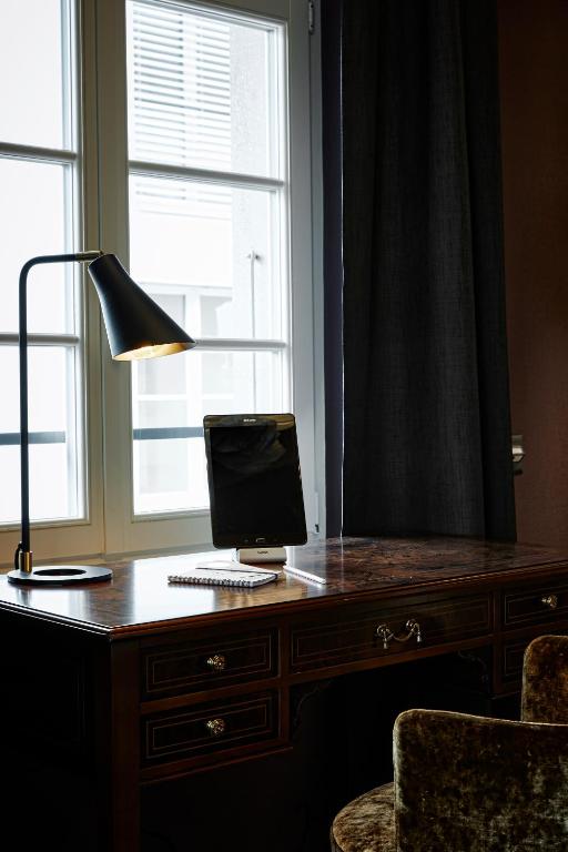a desk with a computer on it with a lamp and a window at Boutique Hotel Spedition a member of DESIGN HOTELS in Thun