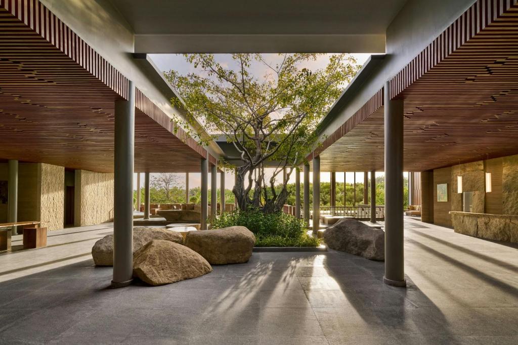 JW Marriott Cam Ranh Bay Resort & Spa في كام رنه: ساحة مع شجرة في وسط مبنى