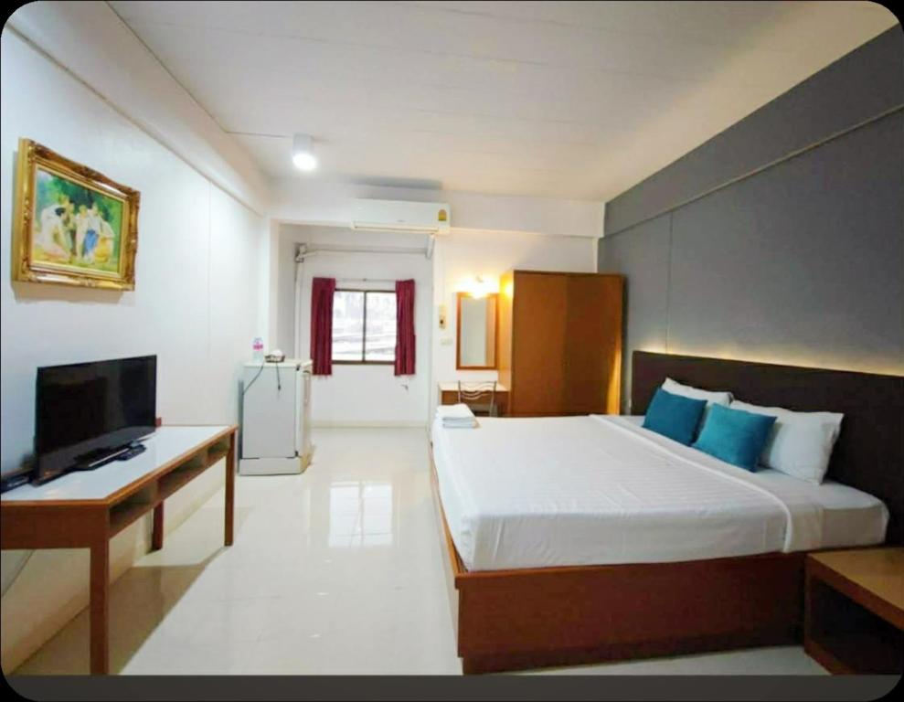 een slaapkamer met een groot bed en een televisie bij Smile Court Pattaya by Mike Group in Pattaya