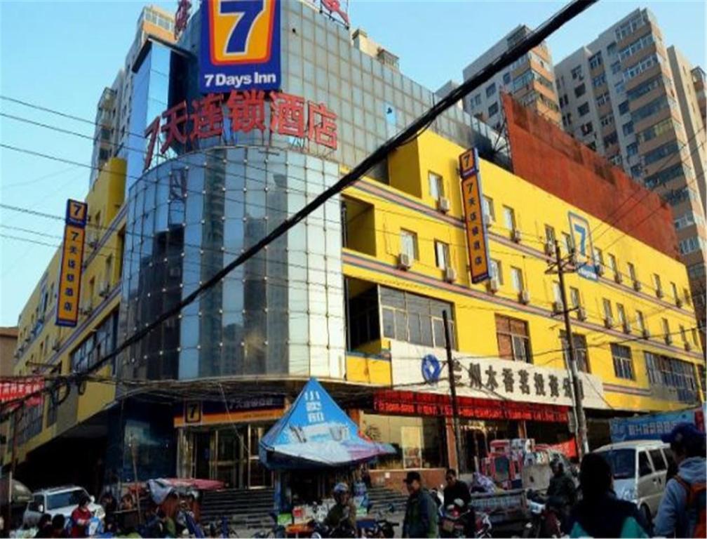 um edifício amarelo com pessoas a andar em frente dele em 7Days Inn Lanzhou West Railway Station em Lanzhou