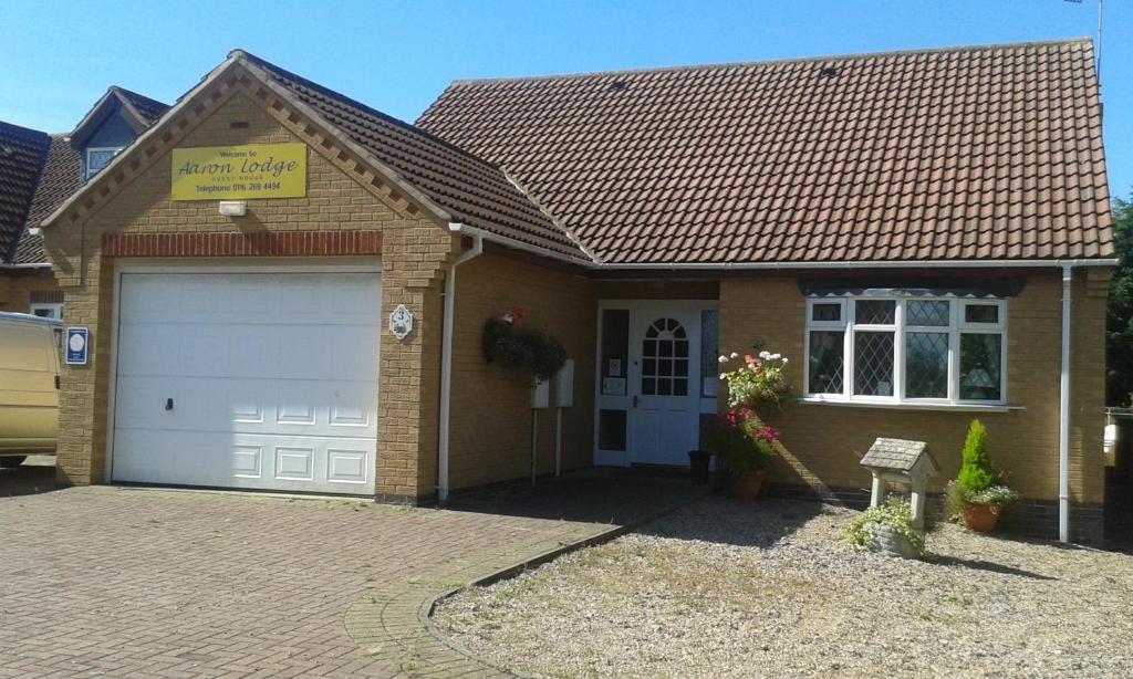 a house with a garage with a sign on it at Aaron Lodge Guest House in Leicester