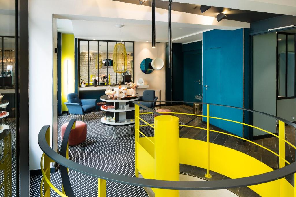 a lobby with yellow and blue walls and a staircase at Hotel Duette Paris in Paris