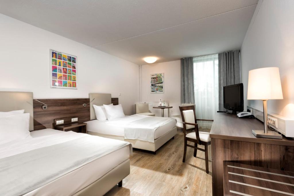 Una habitación de hotel con dos camas y un televisor. en Wyndham Garden Kassel, en Kassel