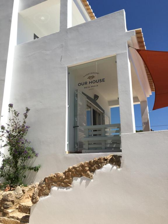 a white building with a sign for our house at Guesthouse Our House in Lagos