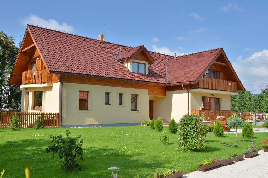 una casa con techo rojo en un patio verde en Apartmany Broma, en Liptovský Mikuláš