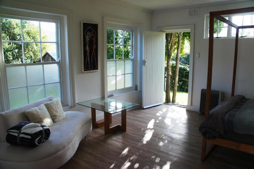 uma sala de estar com um sofá e uma mesa de vidro em Villa Barry em Hout Bay