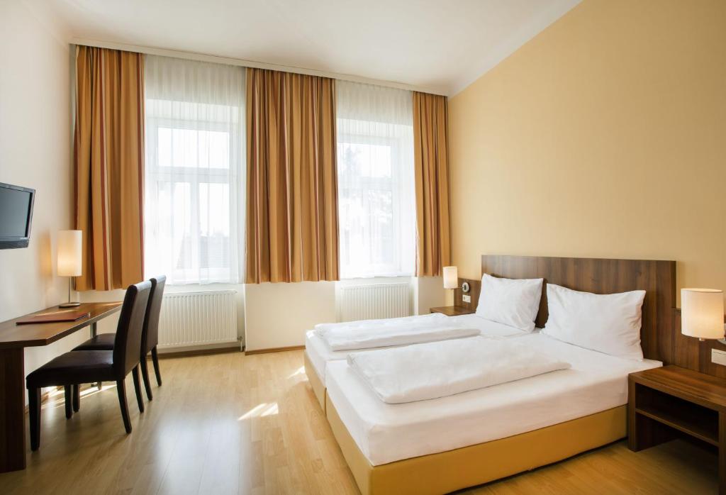 a bedroom with a large white bed and a desk at Hahn Hotel Vienna in Vienna