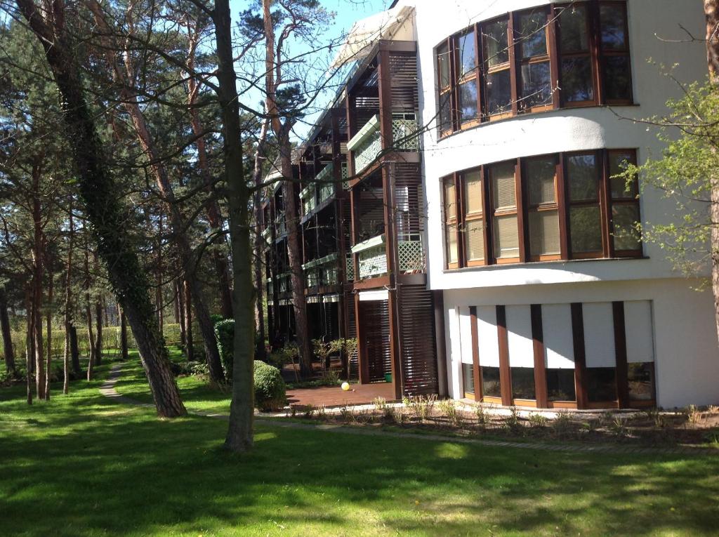 un grand bâtiment blanc avec des arbres devant lui dans l'établissement Apartament Bryza, à Jurata