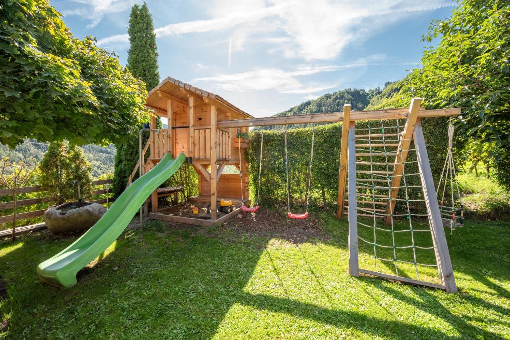 a play house with a slide and swings at Appartements Toni in Feldthurns