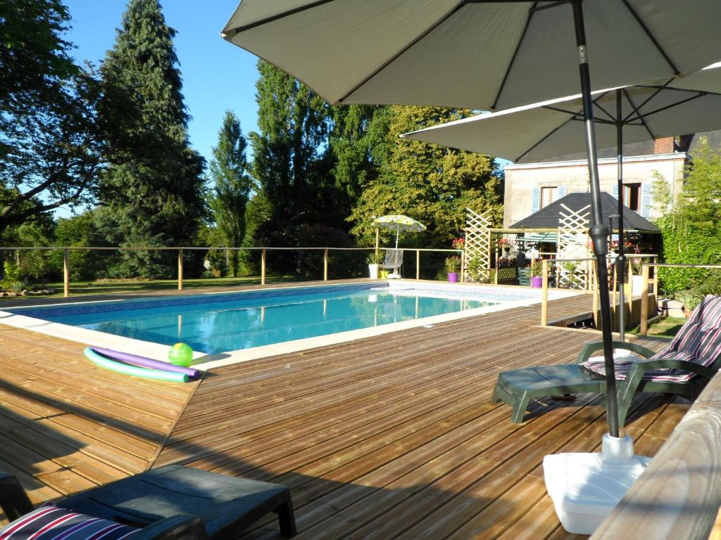a deck with a pool and an umbrella and chairs at Chez Beaumont in Saint-Sébastien