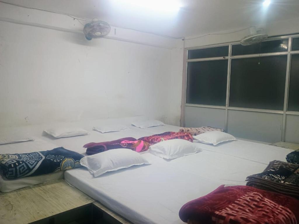 un grande letto bianco con quattro cuscini sopra di SUKH DHAM HOMeSTAy a Prayagraj