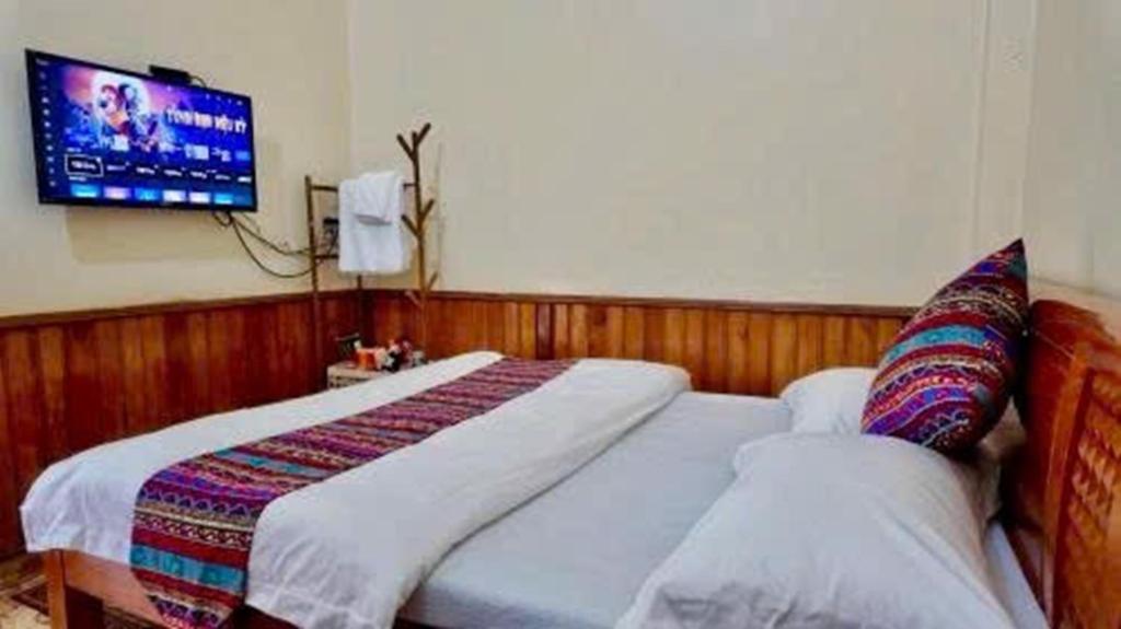 a bedroom with two beds and a tv on the wall at Lien Huong Hostel in Ha Giang