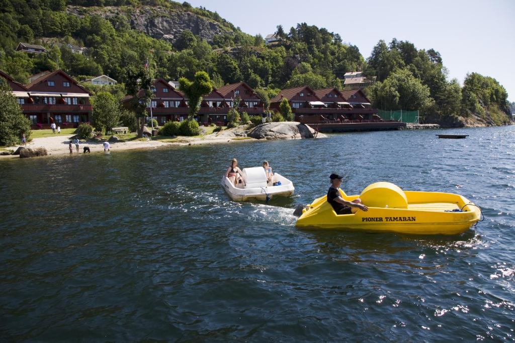 Dos personas montadas en un barco amarillo en el agua en Mones Feriesenter, en Mandal