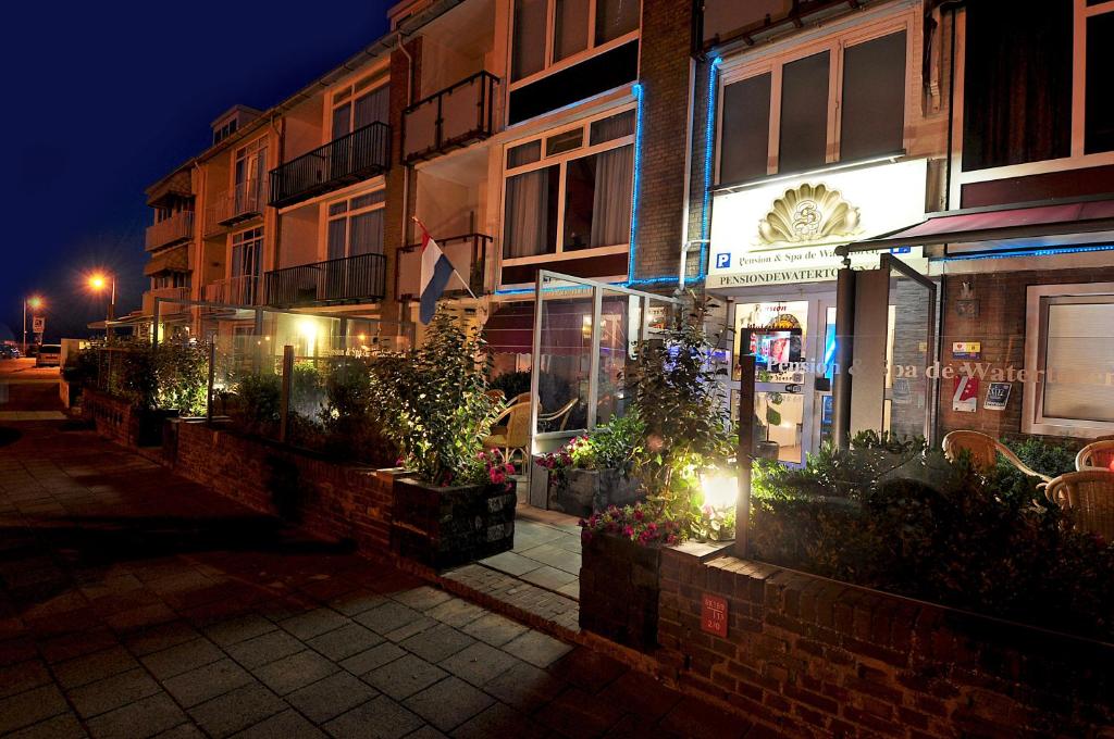 a building with lights on a street at night at Pension & Spa de Watertoren in Zandvoort