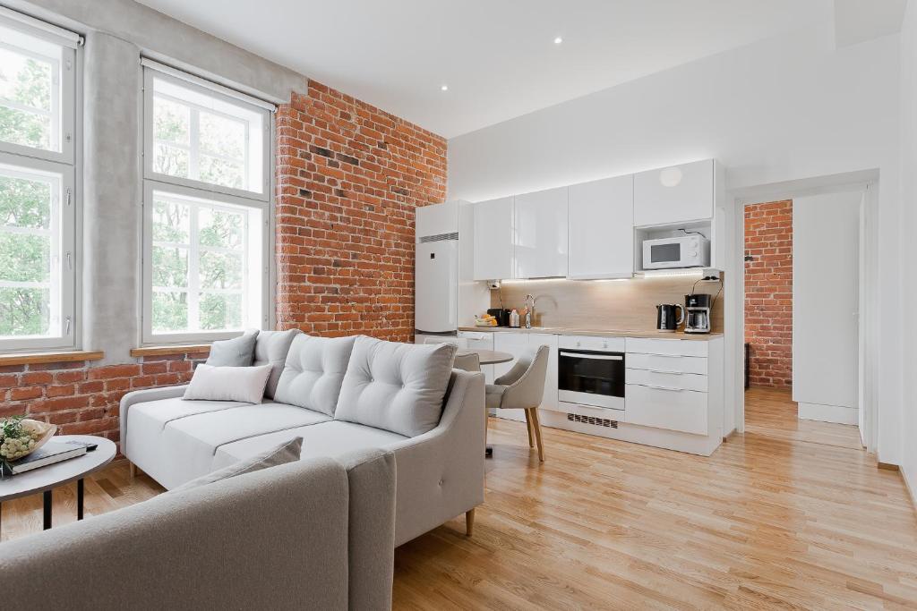 uma sala de estar com um sofá branco e uma parede de tijolos em Forenom Serviced Apartments Turku Kakolanmäki em Turku