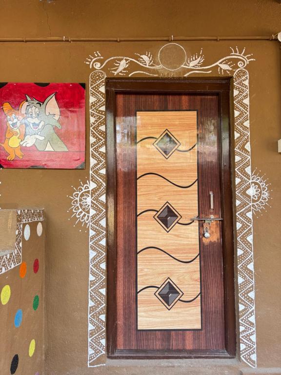 a wooden door with a painting on a wall at Jungle Tree Hampi in Hampi