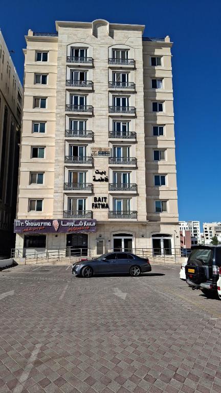 un coche aparcado delante de un gran edificio en Fatima Hostel, en Mascate