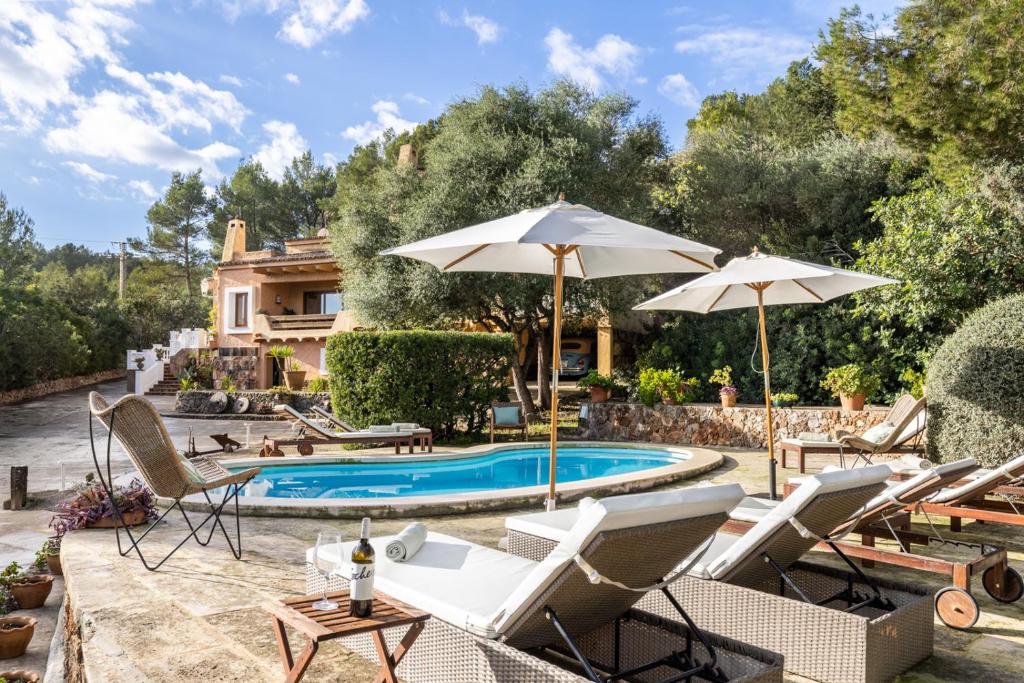 a pool with chairs and umbrellas in front of a house at Lovehaus Terra Rotja in Esporles