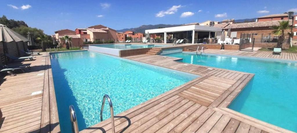 een groot zwembad met blauw water en houten dekken bij Résidence Luna, Saint-Cyprien in Porto-Vecchio