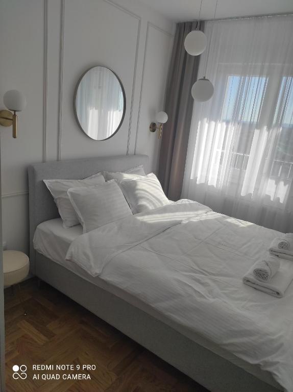 a bedroom with a large white bed with a mirror at Lullaby apartment 2, moderan stan sa spavaćom sobom i privatnom garažom in Bijeljina