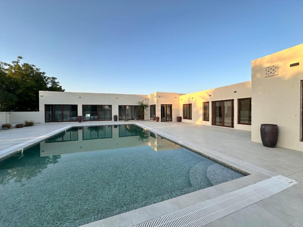 a swimming pool in front of a house at Al Ain Farm Escape with Private Pool , Mini Golf , and Firepit in Bin Aḩmad