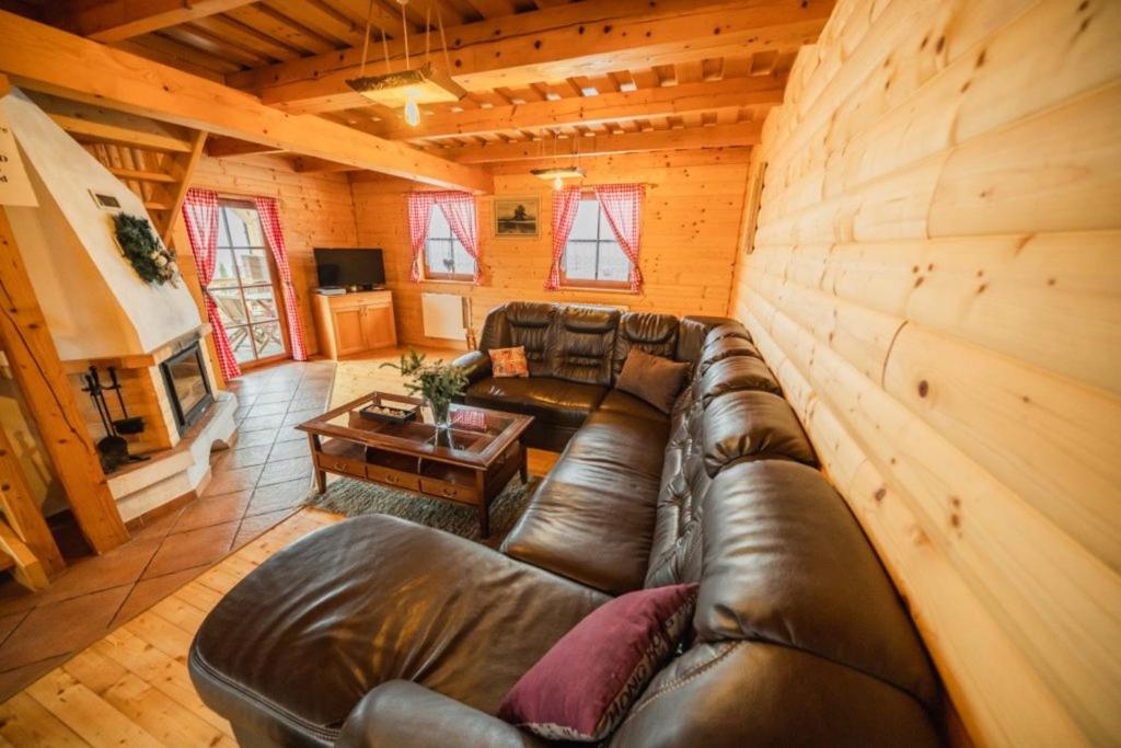 a living room with a leather couch in a cabin at Liptovské Drevenice-chaty in Liptovský Mikuláš