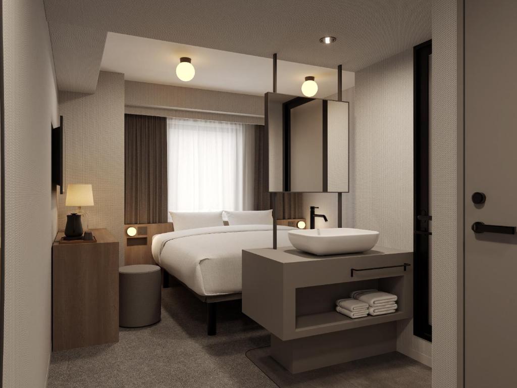 een slaapkamer met een wit bed en een wastafel bij The Knot Utsunomiya in Utsunomiya